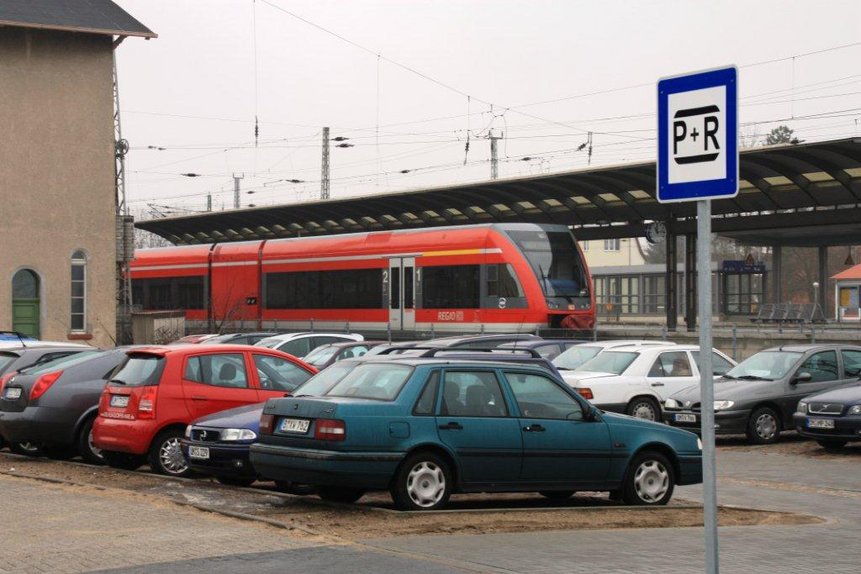 Auto Parkplatz am Bahnhof mit Zug am Bahnsteig