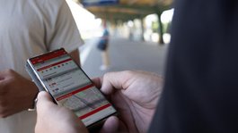 VBB Handyticket Zwei Personen am Bahnsteig. Eine davon hält ein Smartphone mit der geöffneten App.