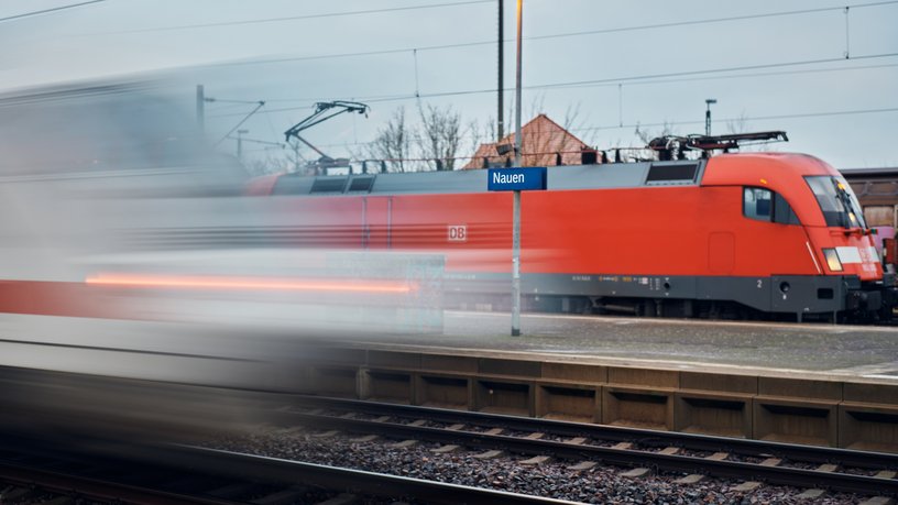 ICE vorbeifahrend an einem Bahnhof an dem eine Regionalbahn steht