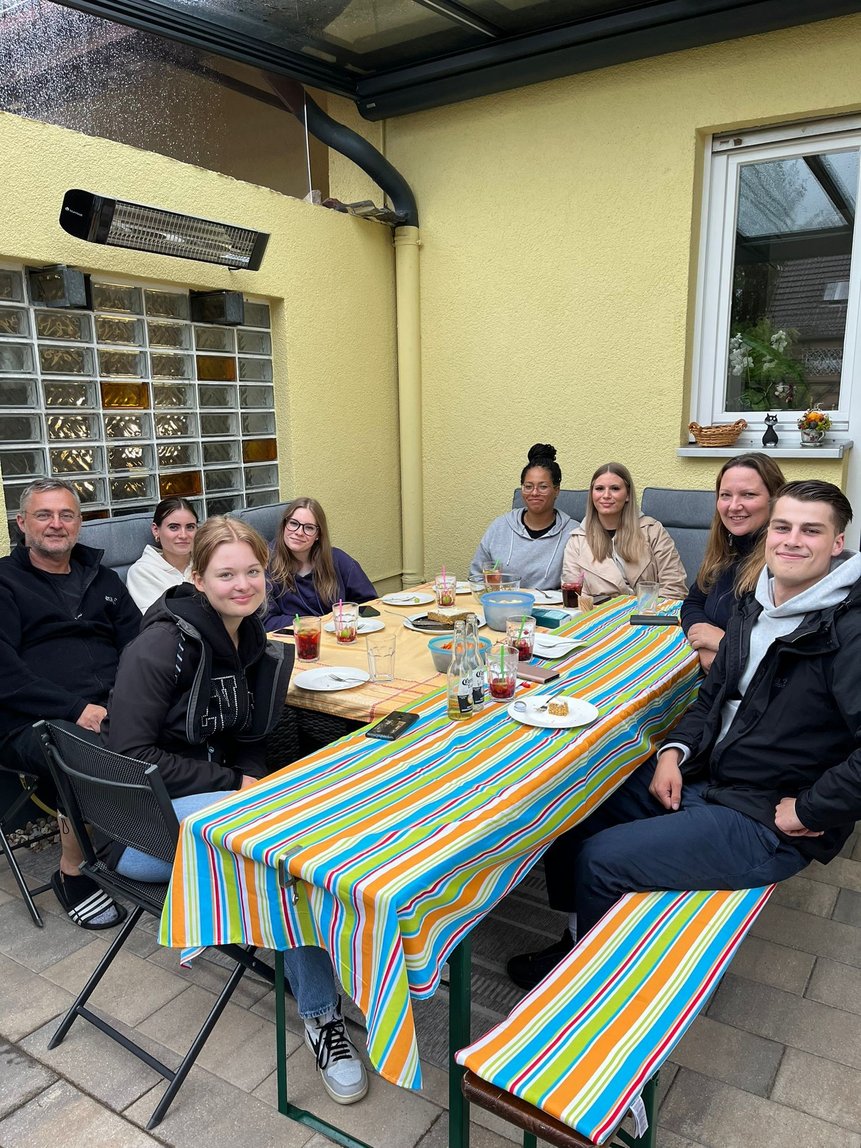 Dies Auszubildenen beim gemeinsamen Grillabend an einem Tisch.